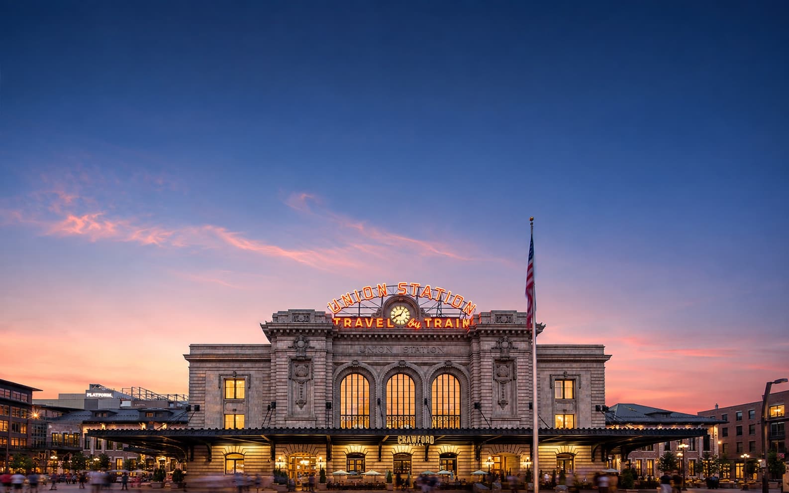 Denver Union Station at dusk, its restored neon sign glowing over the plaza